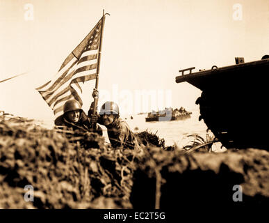 First flag on Guam on boat hook mast.  Two U.S. officers plant the American flag on Guam eight minutes after U.S. Marines and Army assault troops landed on the Central Pacific island on July 20, 1944. Batts. (Marine Corps) Stock Photo