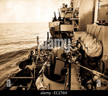 The gun crews of a Navy cruiser covering American landing on the island of Mindoro, Dec. 15, 1944, scan the skies in an effort to identify a plane overhead.  Two 5' (127mm) guns are ready while inboard 20mm anti-craft crews are ready to act.  Navy.  (OWI) Stock Photo