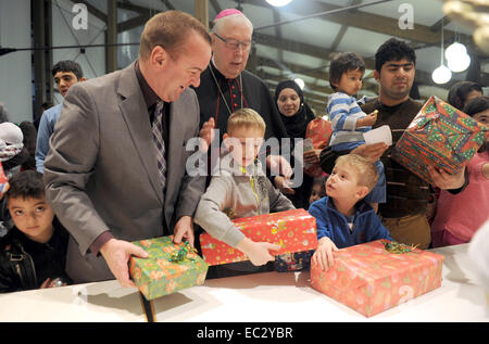 FILE - A file picture dated 16 December 2013 shows Interior Minister of Lower Saxony Boris Pistorius (SPD, L) and bishop of the diocese Hildesheim Norbert Treller (2-L) who hand out gifts during the Christmas party at the Friedland camp for asylum seekers and ethnic German emigrant. This year's Christmas party at the camp will take place on 09 December 2014. Photo: Swen Pfoertner/dpa