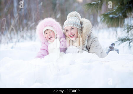 Happy mother and kid lying in snow outdoor Stock Photo