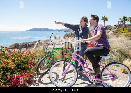 A young couple on bicycles admire the ocean view, Pismo Beach, Central Coast, California, United States of America Stock Photo