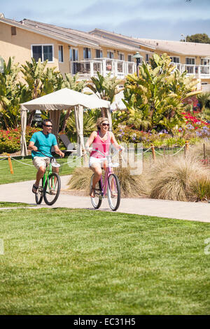young adult couple riding bicycles on a beautiful clear day, Pismo Beach, Central Coast, California, United States of America Stock Photo