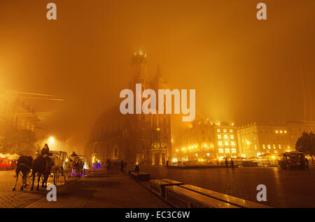 Market square in Cracow at misty night with St. Mary's Basilica with golden sky Stock Photo