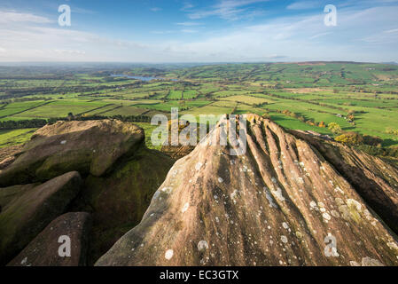 Weathered gritstone rocks on the summit of Hen Cloud with view across a patchwork landscape below.