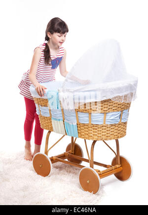 Cute young girl looking at baby sleeping in retro style crib Stock Photo