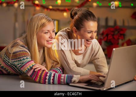 Portrait of happy girlfriends using laptop in christmas decorated kitchen Stock Photo