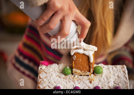 Closeup on teenager girl decorating christmas cookie house with whipped cream Stock Photo