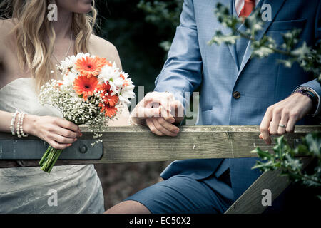 bride and groom behind country gate at vintage village wedding with home made wedding bouquet and groom in shorts, D.I.Y wedding Stock Photo