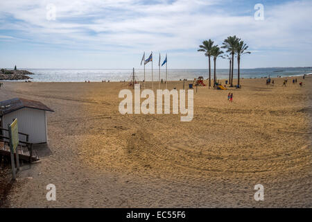 Beach in sunshine, not many people  in the distance, flags flying on the beach Stock Photo