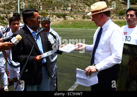 La Paz, Bolivia. 9th December, 2014. The president of Oruro Royal Football Club Jaime Frías (L) gives a book about the team's history to the British Ambassador to Bolivia Ross Denny before a friendly game to remember the 1914 Christmas Truce football match, one of the most iconic events of World War I. A team from the UK Embassy in Bolivia and the Oruro Royal Football Club took part. Credit:  James Brunker / Alamy Live News Stock Photo
