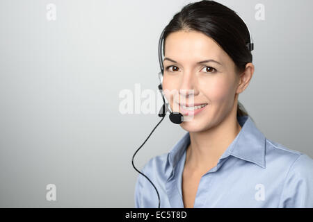 Attractive female call center operator, client services assistant or telemarketer wearing a headset looking at the camera Stock Photo