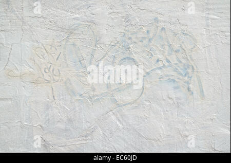 Public graffiti that has been painted over with a light blue paint on an exterior stucco wall. Stock Photo
