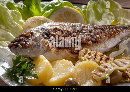 Delicious grilled fish bream, Mediterranean fish, with boiled potatoes and grilled zucchini Stock Photo