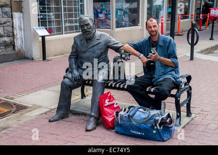 Man sitting on bench beside statue of former mayor, Reverend Gaetz, Red Deer. Alberta, Canada Stock Photo