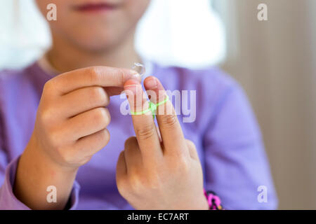 Fingers of little girl making loom bracelets Stock Photo