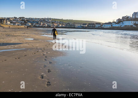 Surfer walking along the water's edge at the beach in Perranporth in Cornwall, UK. - EDITORIAL USE ONLY Stock Photo