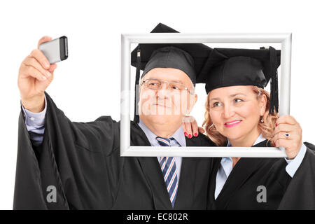 Mature couple taking a selfie behind a picture frame isolated on white background Stock Photo