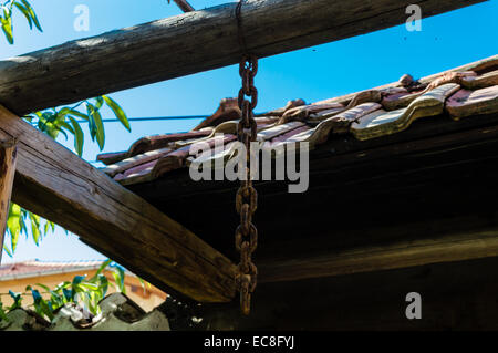 A hanging rusty old chain on a large wooden pillar Stock Photo