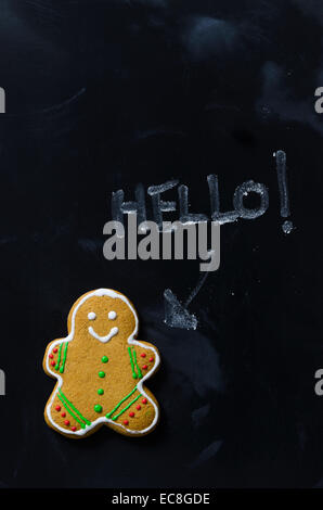 The Gingerbread man say "Hello" over black chalkboard, above view Stock Photo
