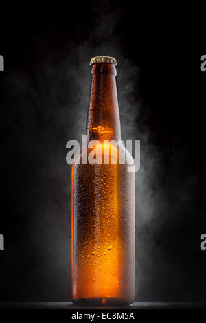 Cold beer bottle with drops, frost and vapour on black Stock Photo