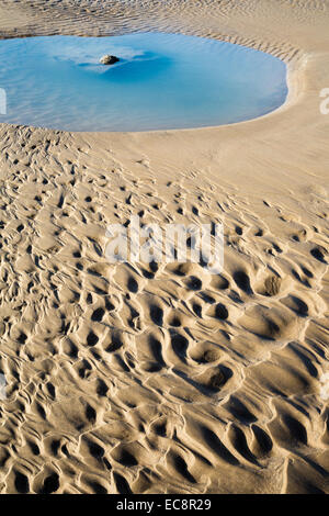 Flow pattern and pool in a sandy beach left by the receding tide Stock Photo