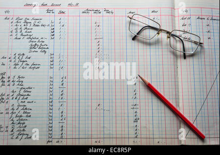 An old accounts ledger, with figures in pounds shillings and pence An accountant's  pencil and glasses lying on the ledger. Stock Photo