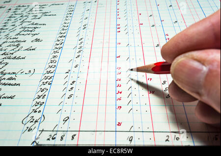 Close up of an accountant checking the figures in an old hand-written bookkeeping ledger. Sums in pounds shillings and pence. Stock Photo