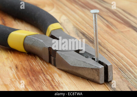 plier and several nails on a wooden table Stock Photo