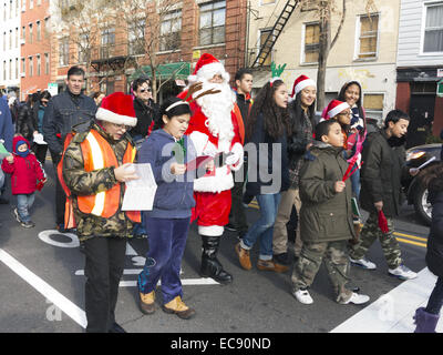 Hispanic Santa leads the Santa Jingle Bell Parade in the Greenpoint section of Brooklyn, NY, 2013. Children caroling. Stock Photo