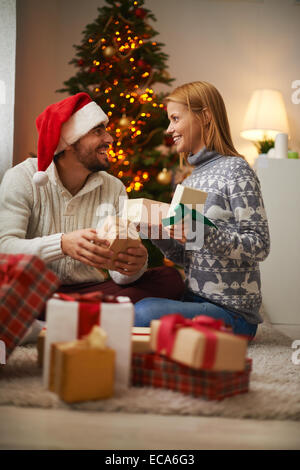 Cheerful couple opening packages with presents on Christmas night Stock Photo