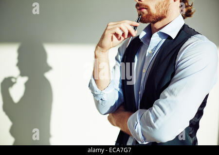 Thoughtful businessman touching chin with pen Stock Photo