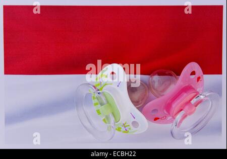 Illustration: Two pacifiers are laying on the flag of the Principality of Monaco, taken in Germany, city of Osterode, 12. December 2014. Photo: Frank May Stock Photo