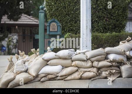 Los Angeles, USA. 11th Dec, 2014. Residents places sandbags to protect their home form mudslides on Thursday, December 11, 2014 in Glendora, California. A storm out of the Pacific Northwest is bearing down on the Southland and expected to start making itself felt tonight. This weather system is threatening heavy rainfall, flash flooding, rivers of mud and debris in areas denuded by wildfire. High surf and perilous rip currents along the coast and winds gusting at as much as 70 miles per hour. Credit:  Ringo Chiu/ZUMA Wire/Alamy Live News Stock Photo