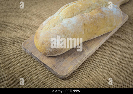 Bread on Bread Board on Burlap Background Stock Photo