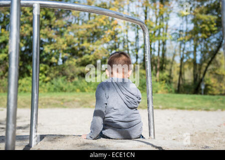 Small lonely boy sitting alone in playground Stock Photo