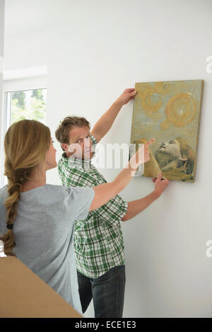 Man hanging painting woman helping explaining Stock Photo