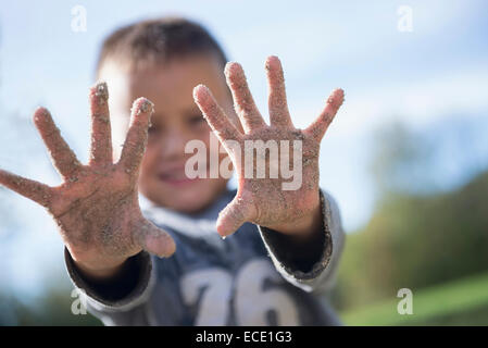 Small boy showing hands covered sand playground Stock Photo