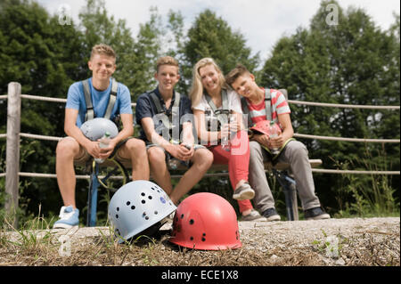 Portrait of teenage boys and teenage girl relaxing on bench, smiling Stock Photo