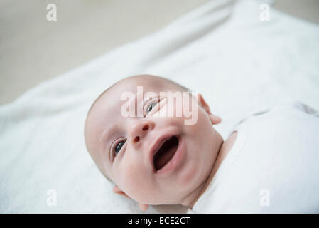 Baby boy lying on bed, smiling Stock Photo