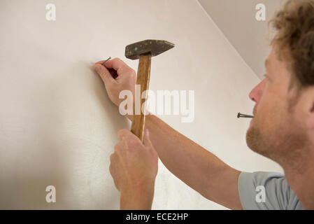 Man hammer nail wall portrait close-up Stock Photo