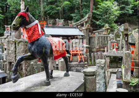 Statue of a sacred horse in a Shinto graveyard, on the mountainside at the shrine of Fushimi Inari-taisha, Kyoto, Japan Stock Photo