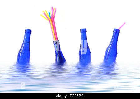 Blue bottles with coloured straws floating in water Stock Photo