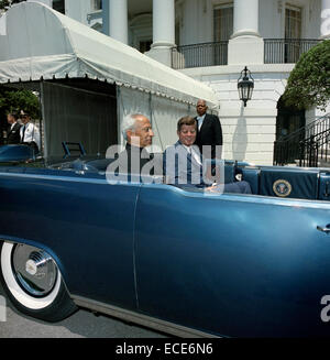 US President John F. Kennedy and President of India, Dr. Sarvepalli Radhakrishnan, sit in the back seat of the presidential limousine before the start of a parade in honor of President Radhakrishnan at the south portico of the White House June 4, 1963 in Washington, DC. Special Assistant to President Kennedy, John J. McNally (head turned), stands at far left in background; an unidentified White House staff member stands at center in background. South Lawn driveway, White House, Washington, D.C. Stock Photo