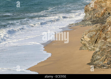 Waves breaking on a sandy beach at Loe bar near Porthleven, Cornwall, UK on a sunny winters day.  The incoming tide is breaking on  the rocks Stock Photo