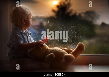 Boy and teddy bear watching sunset Stock Photo