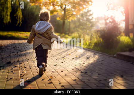 Boy running towards rising sun Stock Photo