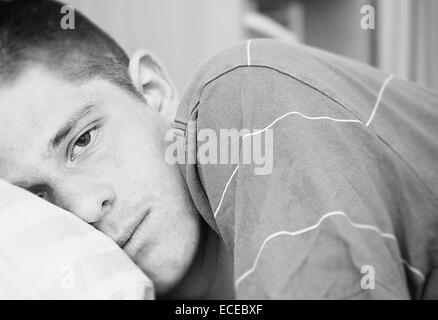 Portrait of teenage boy lying in bed Stock Photo