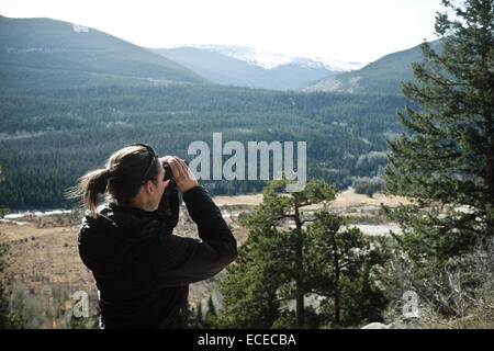 Woman looking at landscape view through binoculars Stock Photo