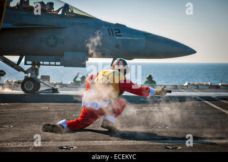 A US Navy sailor wearing a Santa Claus costume serves as a flight shooter as he launches a F/A-18F Super Hornet fighter aircraft on the flight deck aboard the Nimitz-class aircraft carrier USS Carl Vinson December 12, 2014 in the Arabian Gulf. The ship is supporting Operation Inherent Resolve, strike operations in Iraq and Syria against Islamic State targets. Stock Photo