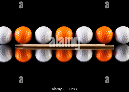 White and orange golf balls with bamboo chopsticks on the glass  table Stock Photo